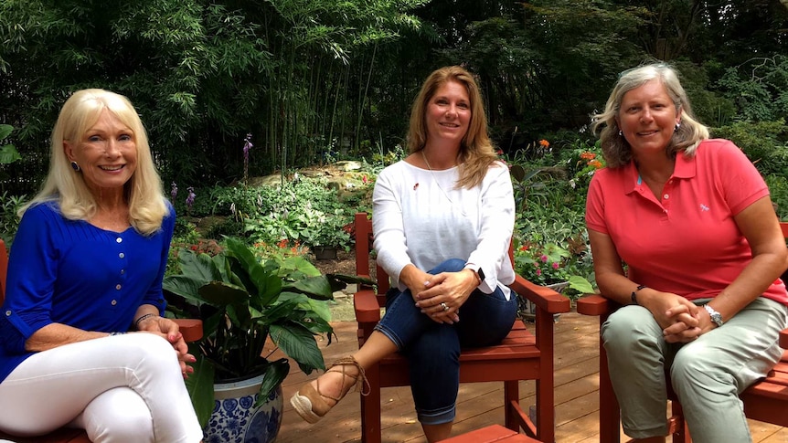 Three members of the Virginia Women for Trump group sit in garden chairs and smile at the camera