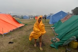 A woman battles a downpour at a relief camp for earthquake survivors