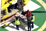 A woman on a stretcher being taken out of a helicopter. 