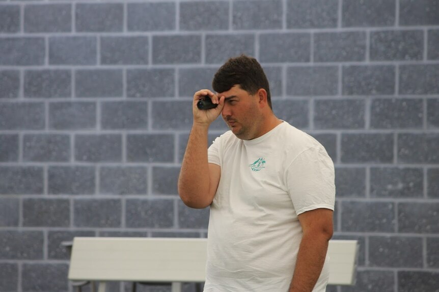 Para-Athlete Jake Fehlberg using a monocular to help him when playing lawn bowls