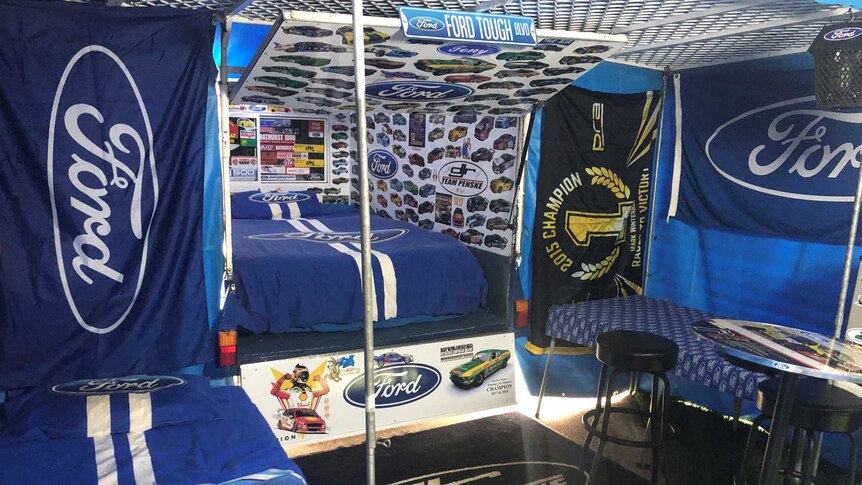 A caravan is decked out with Ford flags and stickers.
