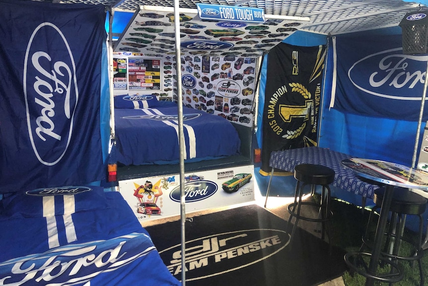 A caravan is decked out with Ford flags and stickers.