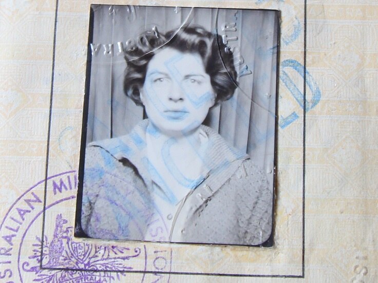 An old black and white passport photo of a woman with dark curly hair.