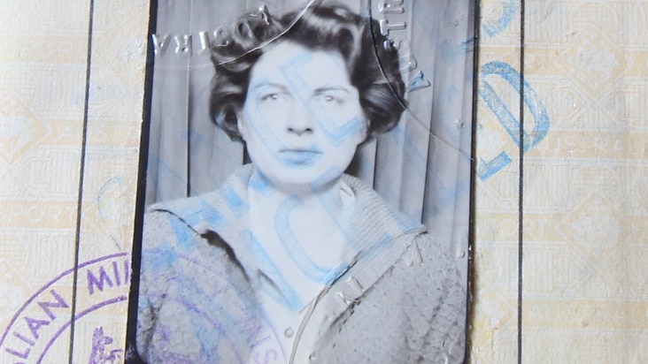 An old black and white passport photo of a woman with dark curly hair.