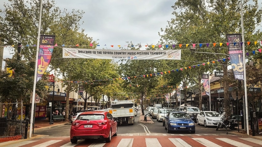 a road in a main busy street with a banner above saying welcome to the toyota country music festival tamworth