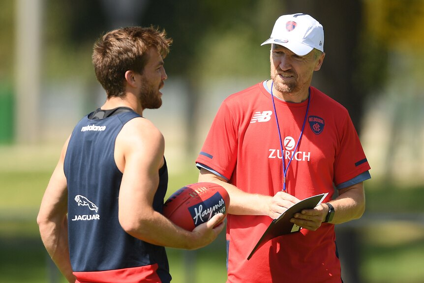 AFL fitness coach talking with a player during training 