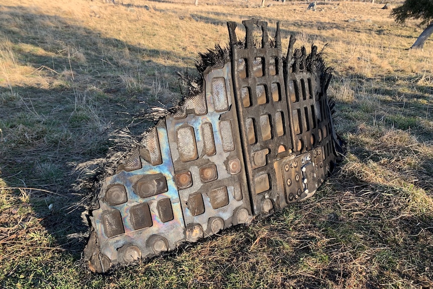 a piece of space junk lies on the ground in a paddock