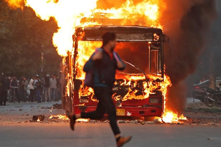 Protestor walks past a truck on fire in India.