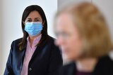 Annastacia Palaszczuk in a mask watches as Jeannette Young speaks to reporters