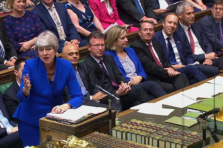 Theresa May appears in the House of Commons' dispatch box in an electric blue suit as she gestures across the chamber.