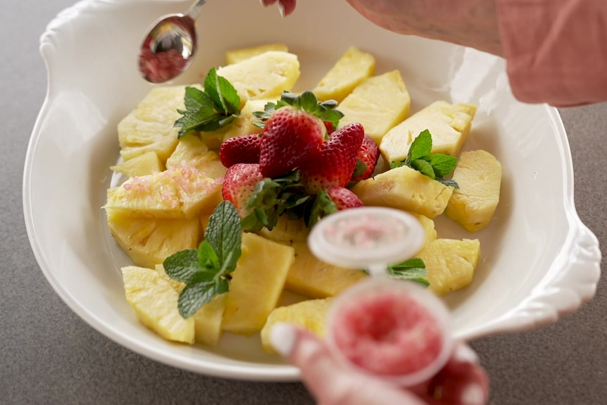 Photo of a fruit salad with pineapple, mint, strawberries and fingerlime.