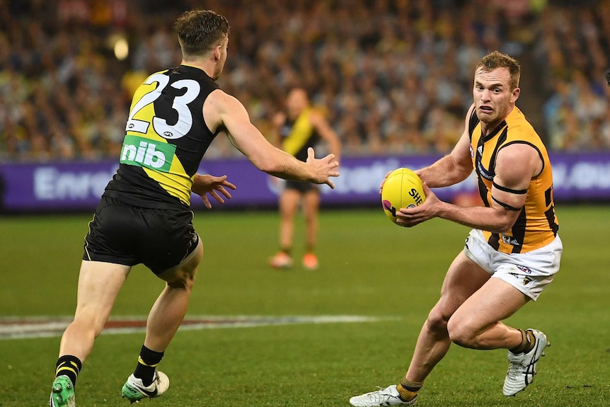 Tom Mitchell with the ball as he tries to beat the defence of Kane Lambert.