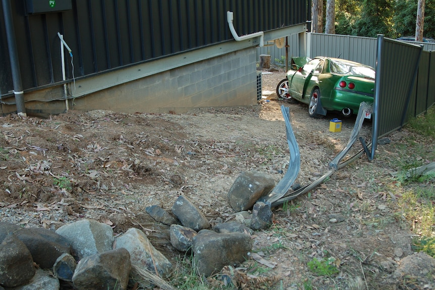 A crashed car at the bottom of a slope.