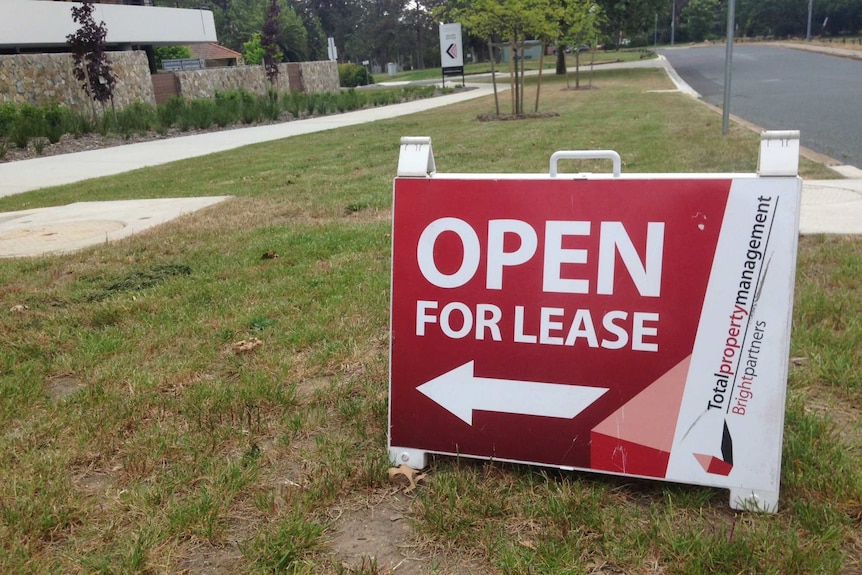 A "for lease" sign on a footpath outside a property.