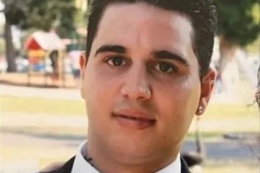 Josh Kerr, dressed in a white shirt, blue tie and jacket, appears in a portrait photograph.