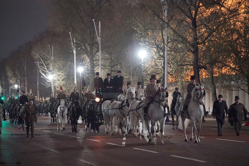 People ride on horseback through the Mall at night