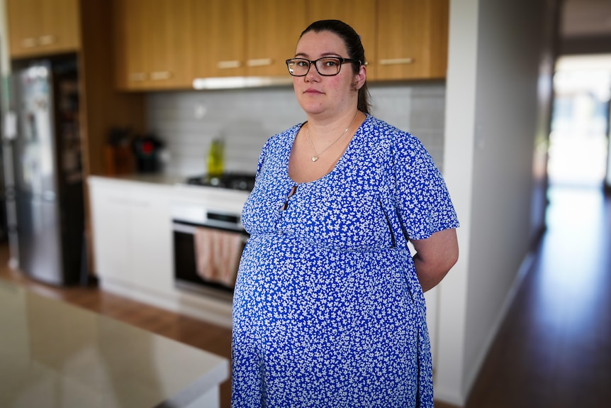 Una mujer embarazada parada dentro de una casa.