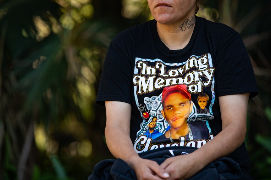 A woman wearing a t-shirt with the workds 'In loving memory of Cleveland' with photos of a young Aboriginal boy.