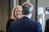 Blonde woman talking to a man in a room