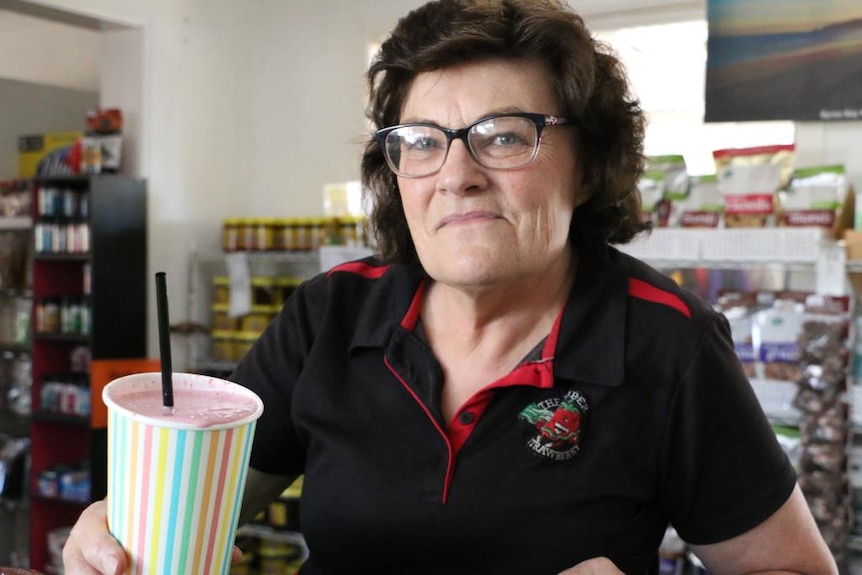 Cecily Woodlands stands at the counter of the Super Strawberry holding a strawberry milkshake up.