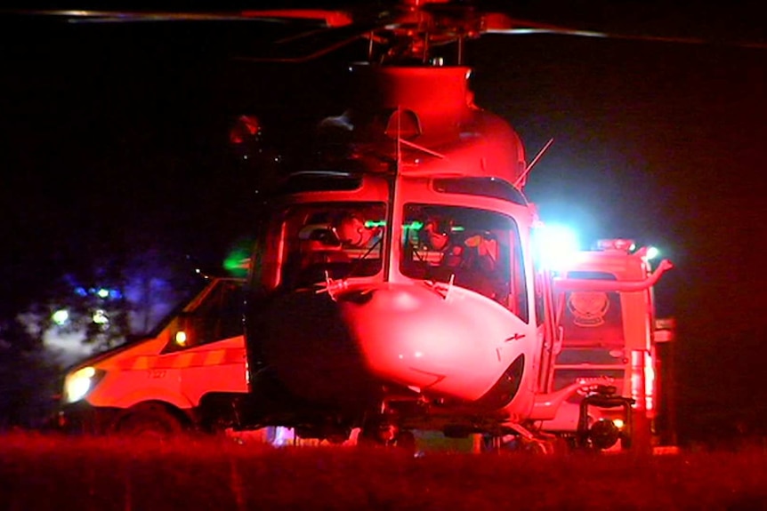 An Air Ambulance in front of an ambulance van at night, lit by red-and-blue emergency services lights.