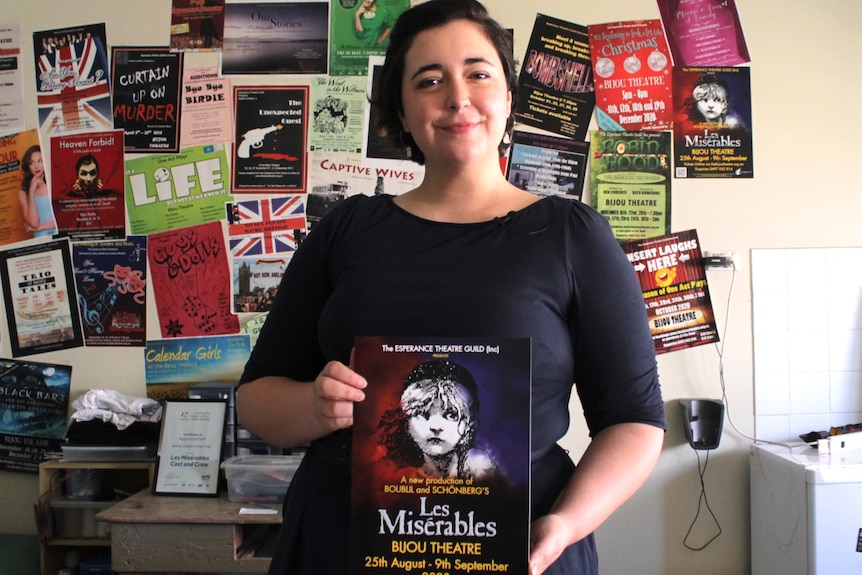 A woman holds a copy of a poster for Les Miserables.