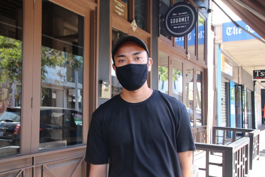 A man in black clothing and mask pictured outside a restaurant