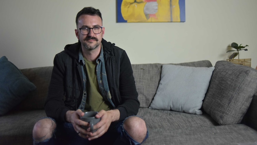 Patrick McIvor sitting on couch in lounge room with mug