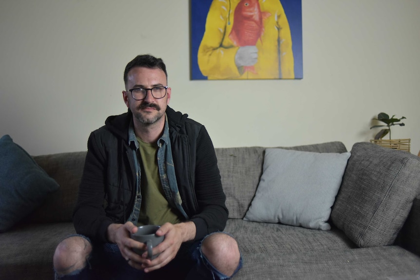 Patrick McIvor sitting on couch in lounge room with mug