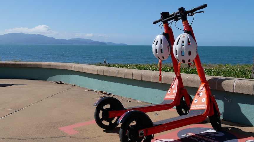 Two e-scooters parked with a beach backdrop