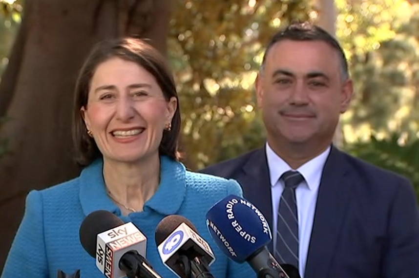 A man and a woman standing in front of media microphones.