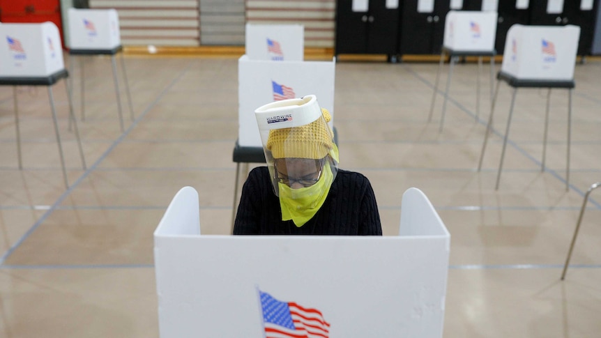 Jocelyn Bush, a poll worker at the Edmondson Westside High School Polling site, cleans each station after a ballot is cast