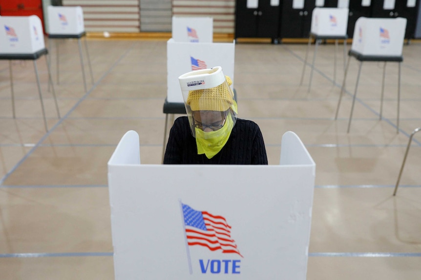 Jocelyn Bush, a poll worker at the Edmondson Westside High School Polling site, cleans each station after a ballot is cast