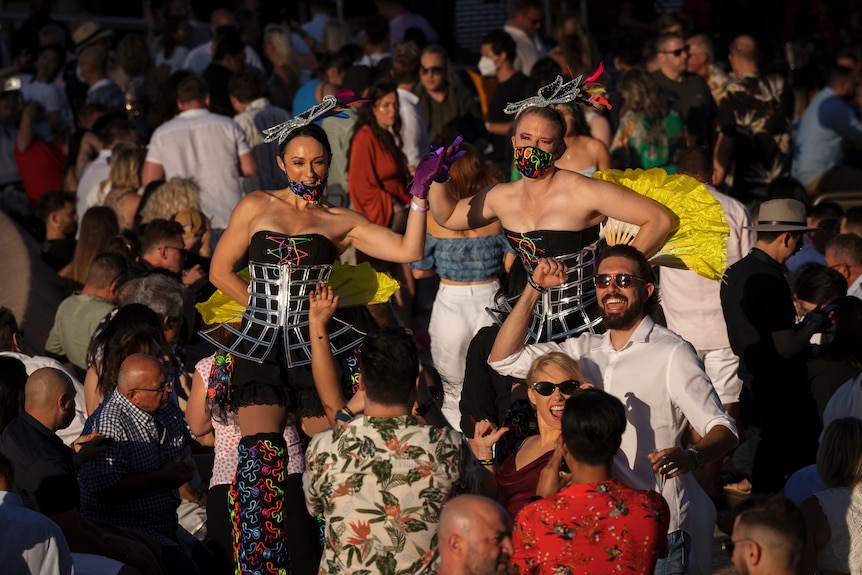 Performers smile at camera among crowds 