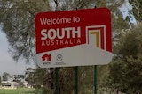 A sign saying Welcome to South Australia with trees behind