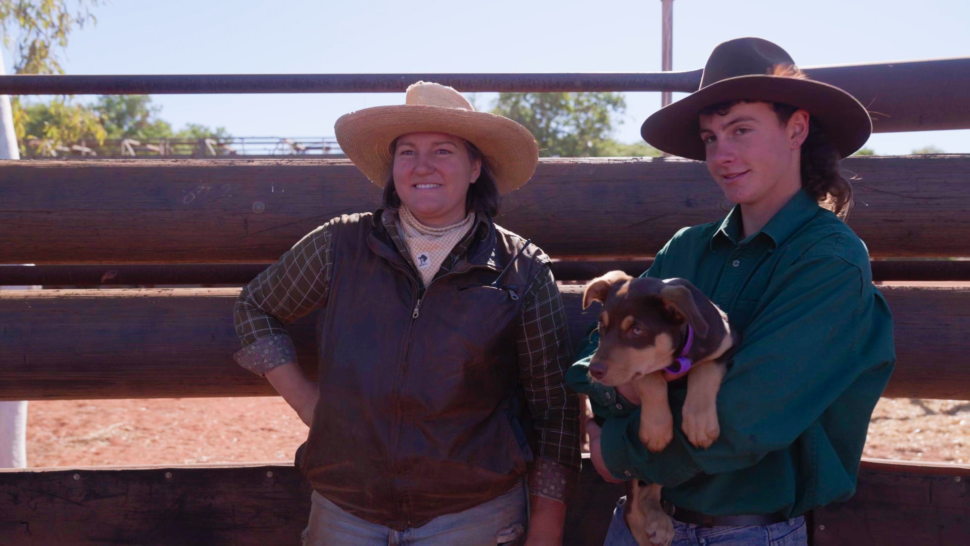 Una mujer junto a un adolescente sostiene un cachorro de Kelpie.