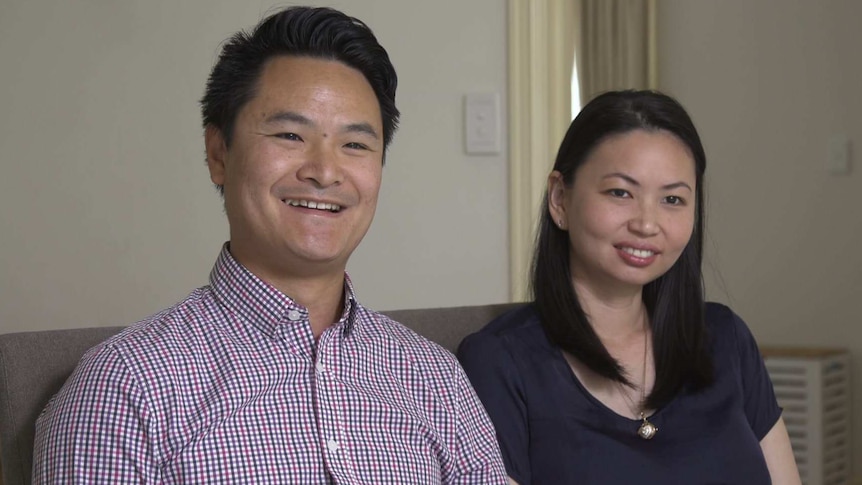 Alex and Emily Truong sit on a couch.