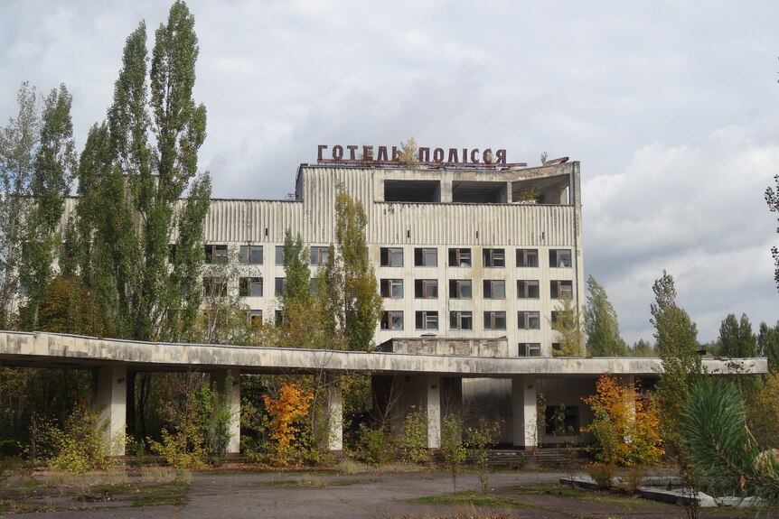 A dilapidated building stands next to a ruined road and trees next to Ukraine.