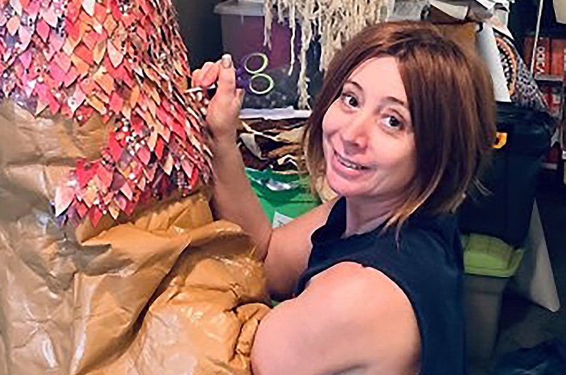 A woman smiles as she works on creating a dress