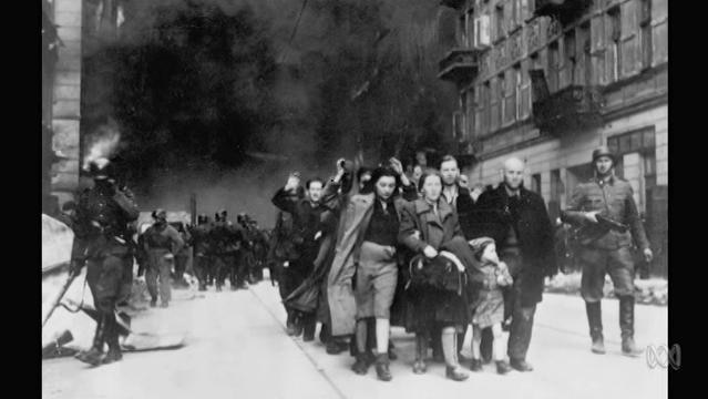 Old photo of Polish Jews being marched through the street by soldiers