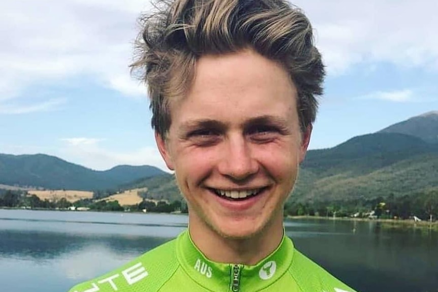 A young man in a cycling jersey smiling