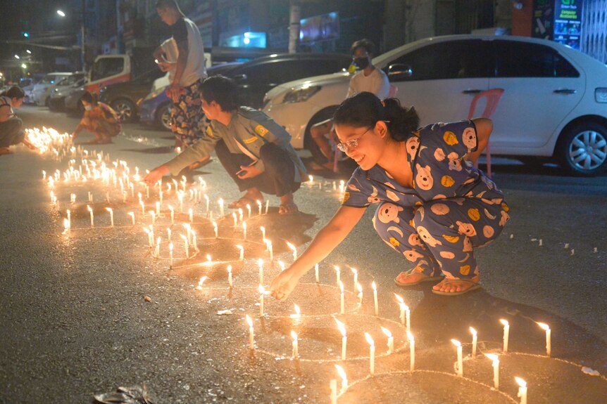 Les gens allument des bougies dans la rue lors d'une veillée aux chandelles à Yangon