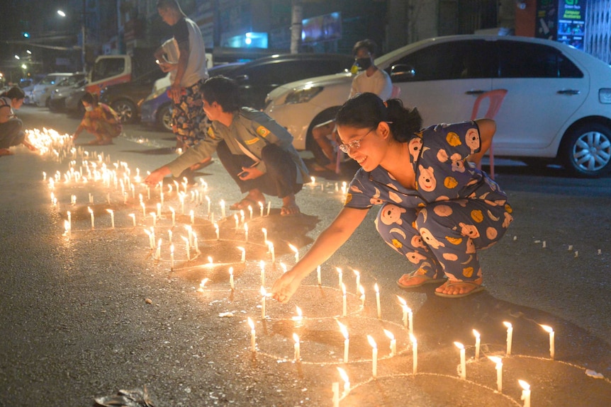 People light candles on the street during a candlelit vigil in Yangon