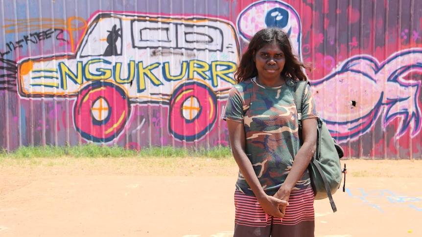 Mary-Beth Rogers stands in front of a wall of graffiti