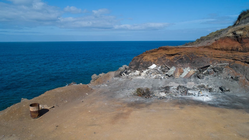 Photograph of a cliff top on Norfolk Island where waste is thrown into the ocean.