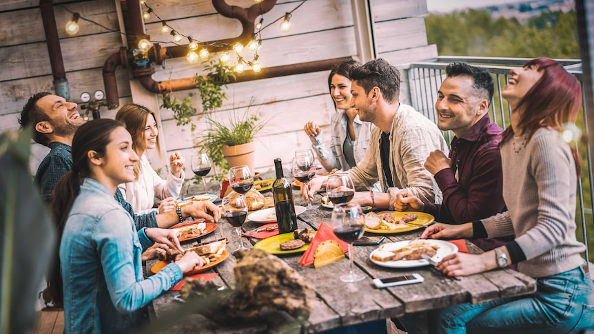 A group of young people enjoying an evening outside with wine and food