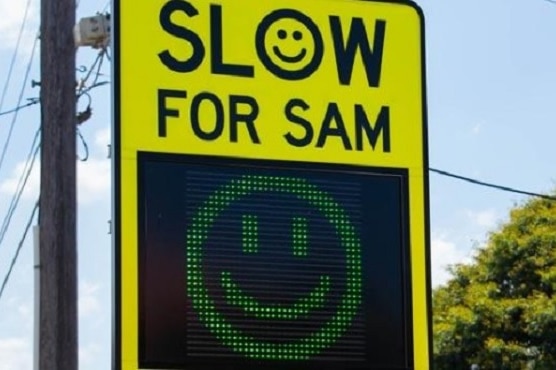 A 'Slow For SAM' sign with a smiley face