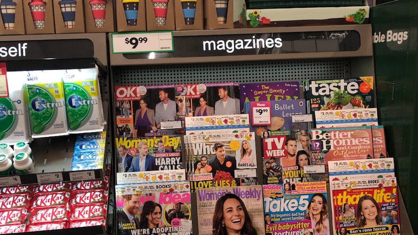 Magazines sit on the shelf next to soft drinks at the supermarket checkout