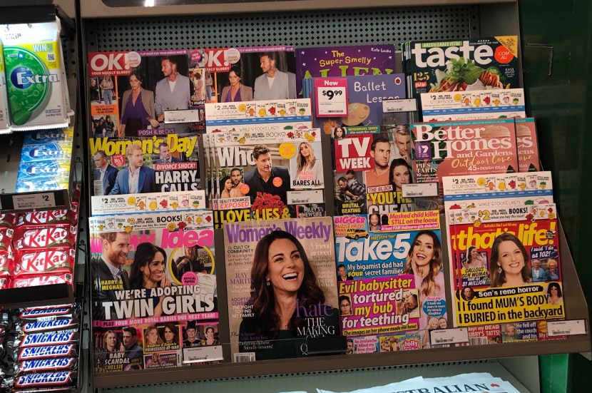 Magazines sit on the shelf next to soft drinks at the supermarket checkout