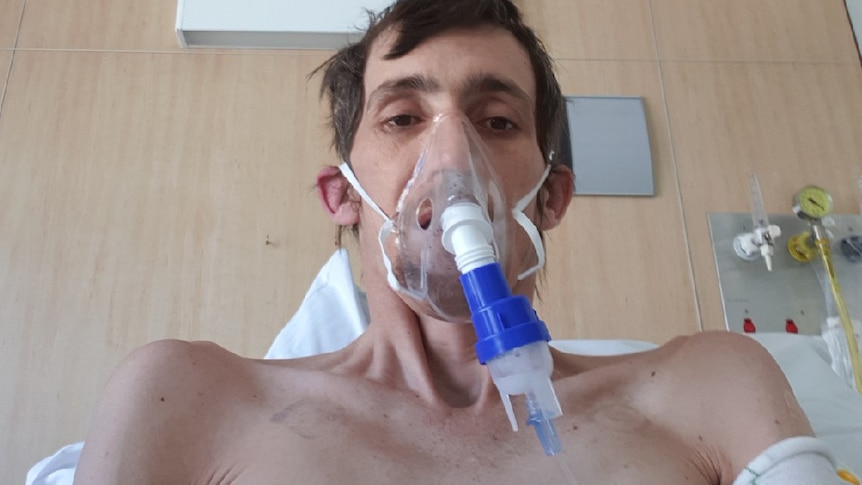 Gold Coast stonemason Anthony White sits up in a hospital bed in intensive care.